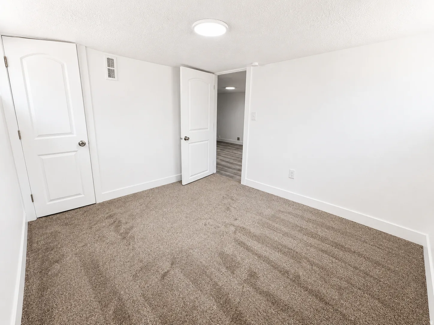 Neutral-toned carpet flooring and white walls create a blank canvas