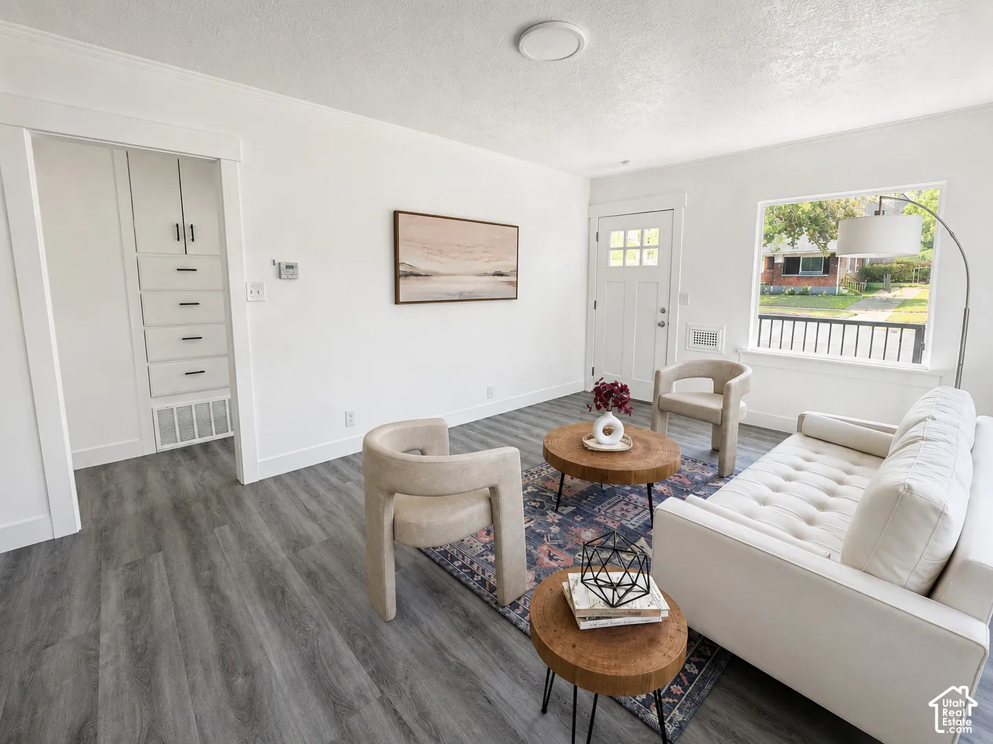 Spacious living area featuring contemporary gray wood-finish flooring, white trim, and a built-in storage cabinet with matte black hardware