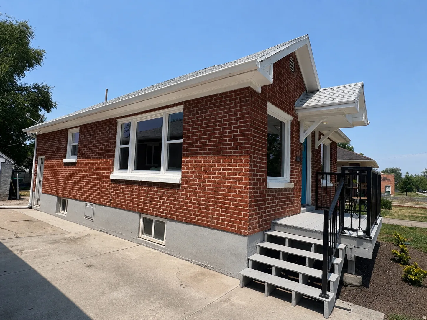 Red brick exterior with white trim, featuring a newly constructed front porch and steps with black railings