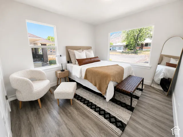 Spacious room featuring wood-finish flooring, two large windows, and bright white walls
