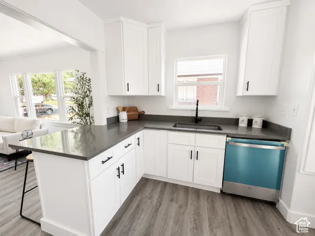 Modern kitchen featuring white shaker cabinetry with matte black hardware, gray countertops, and wood-finish flooring