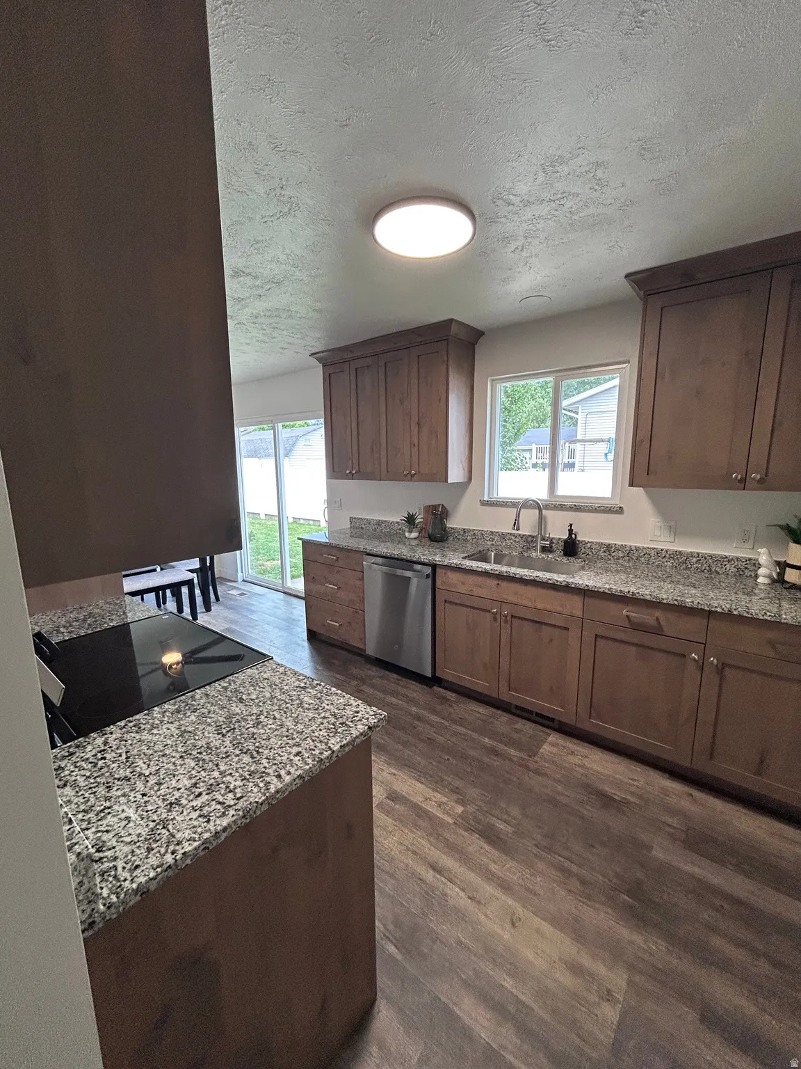 Kitchen featuring wood-finish flooring, granite countertops, stainless steel appliances, and wood cabinetry