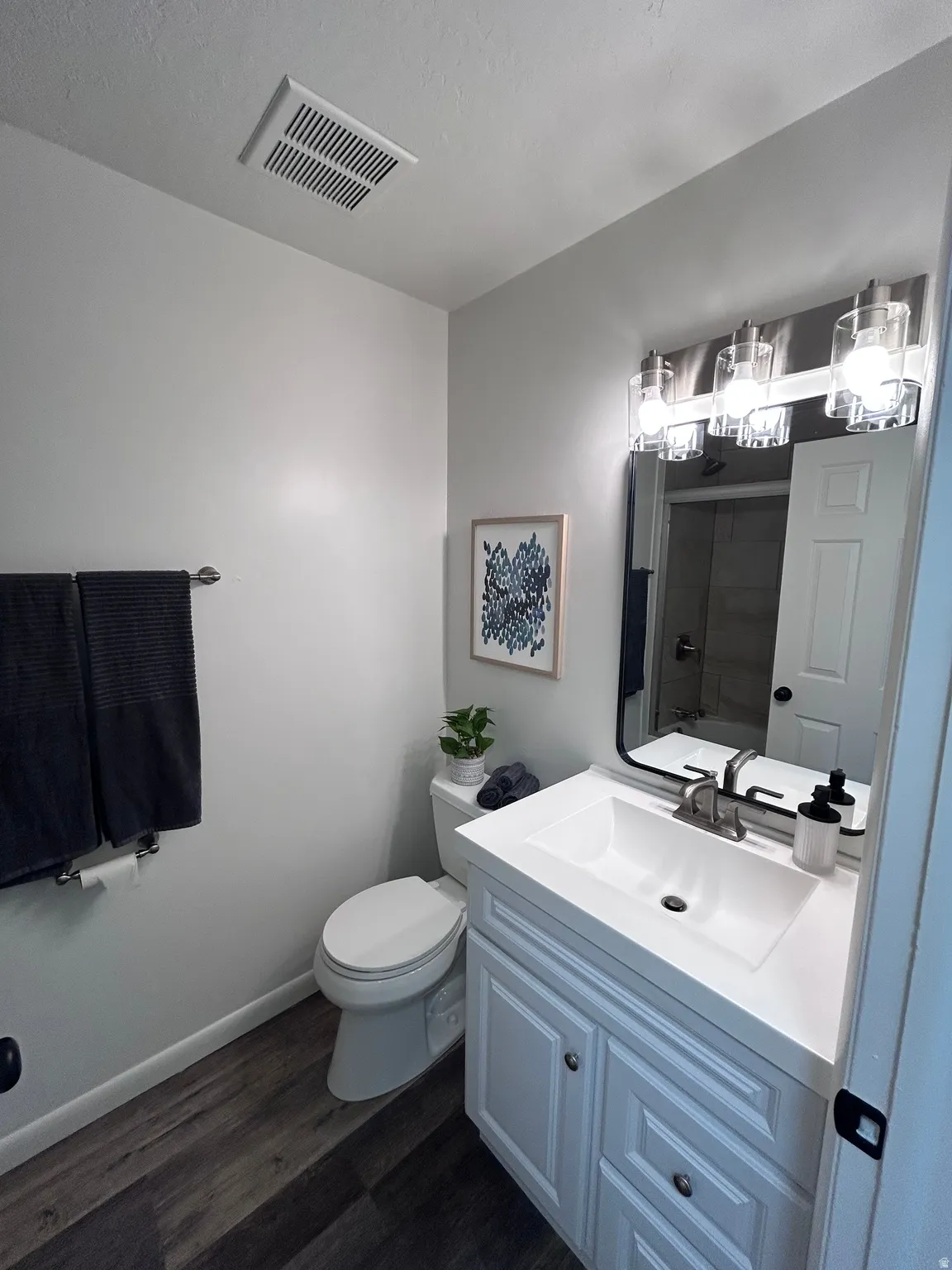 Bathroom featuring a white vanity with integrated sink, brushed nickel faucet, and a contemporary three-light fixture