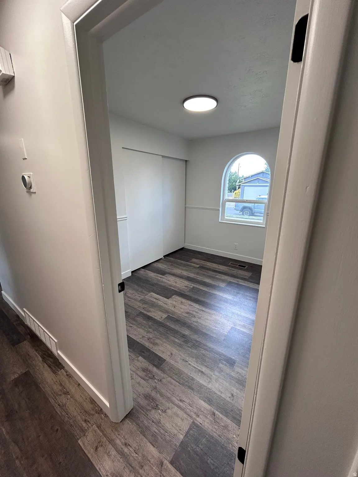 Room featuring wood-finish flooring, white walls, and a contemporary ceiling light fixture