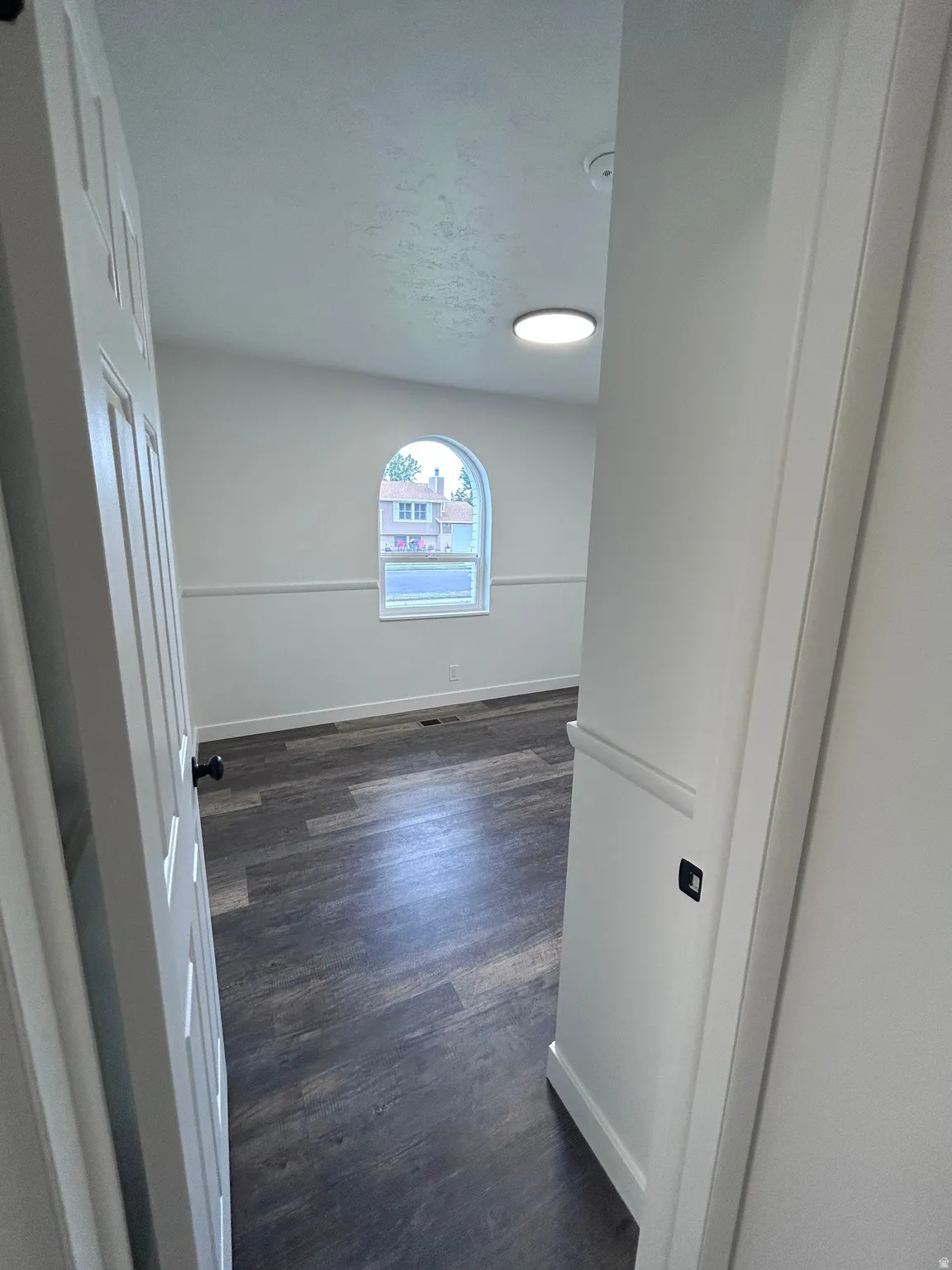 Room featuring wood-finish flooring and a distinctive arched window