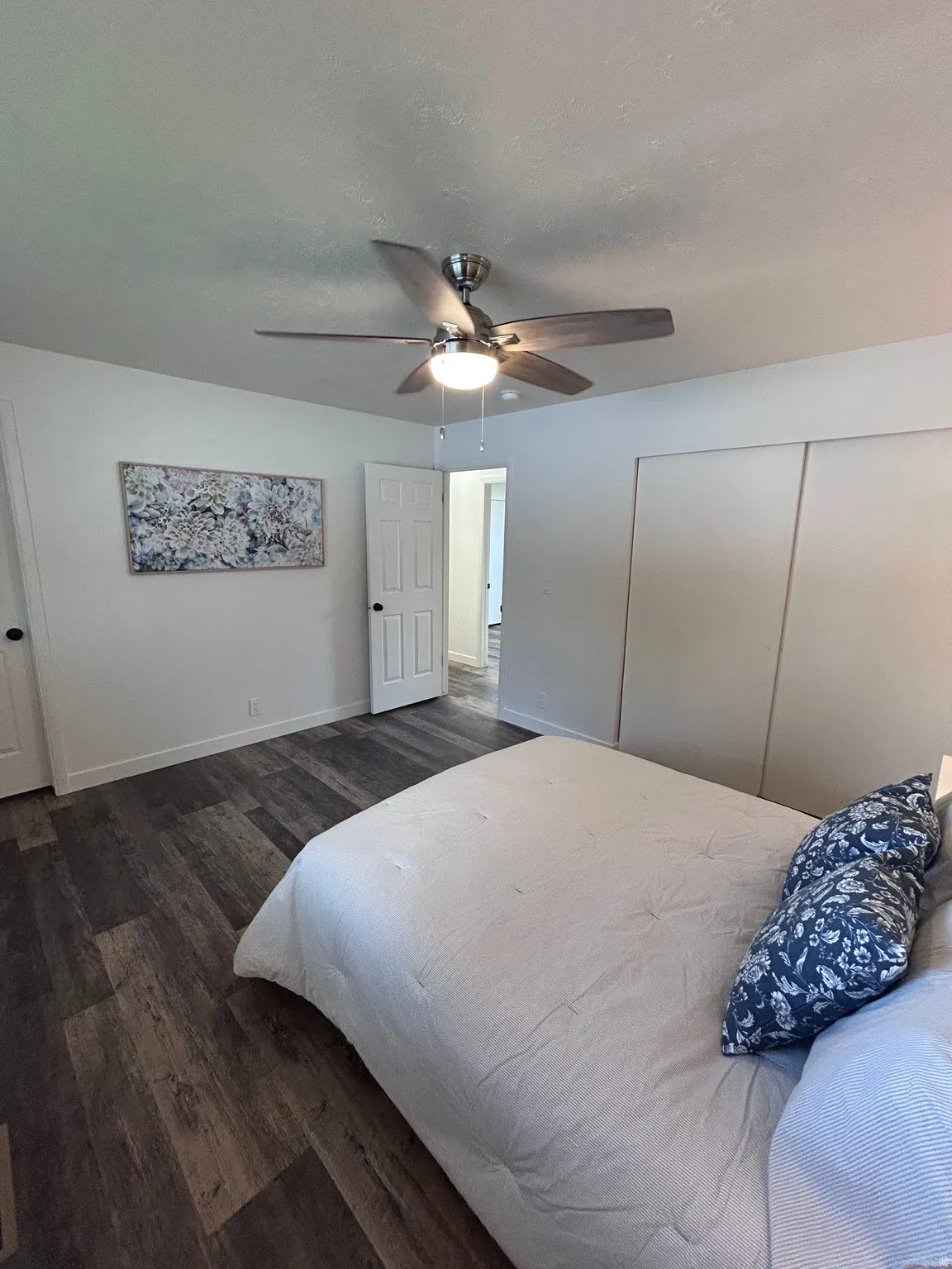 Bedroom featuring wood-finish flooring, a ceiling fan with integrated lighting, and white sliding closet doors