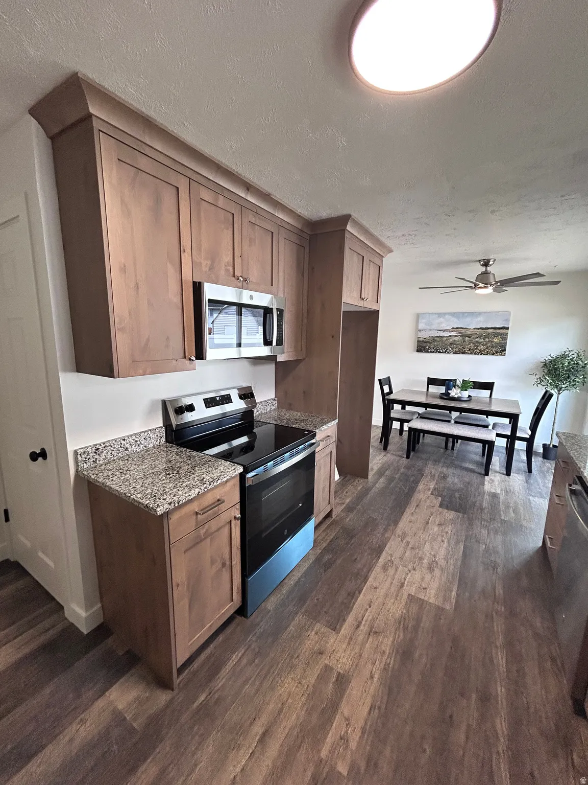 Contemporary kitchen featuring wood-finish cabinetry, stainless steel appliances, and speckled countertops
