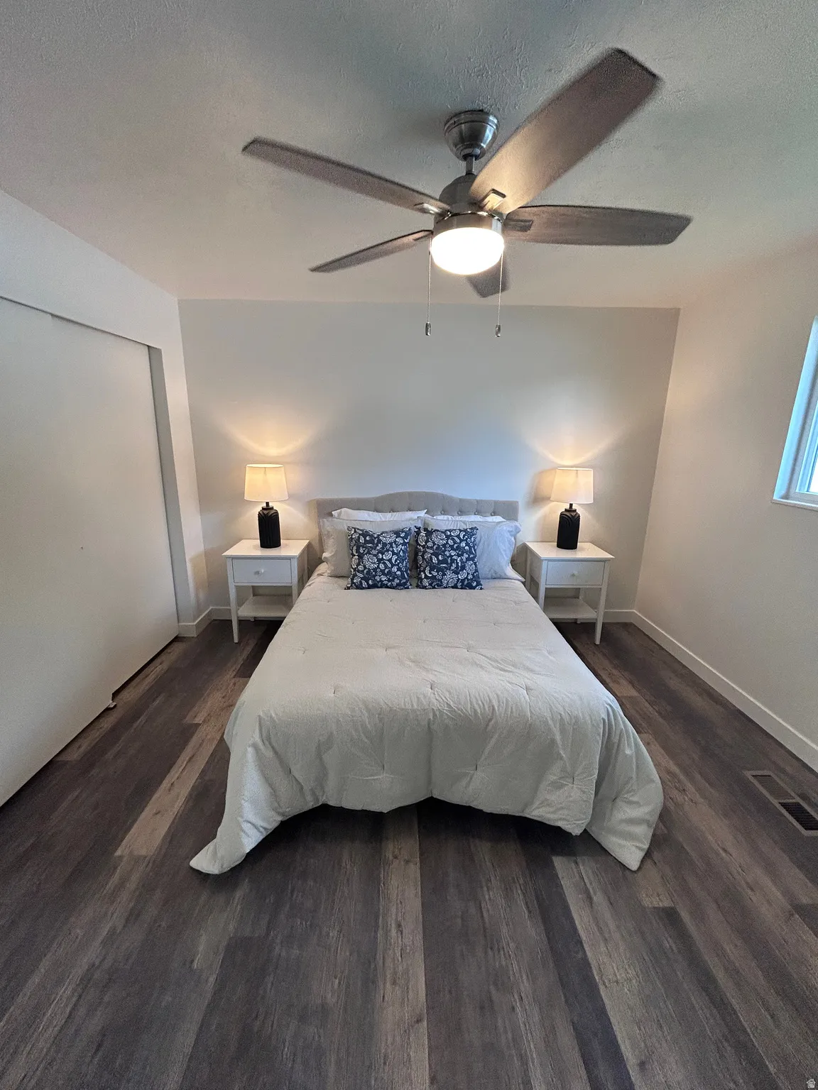 Bedroom featuring wood-finish flooring, a ceiling fan with integrated lighting, and a window providing natural illumination