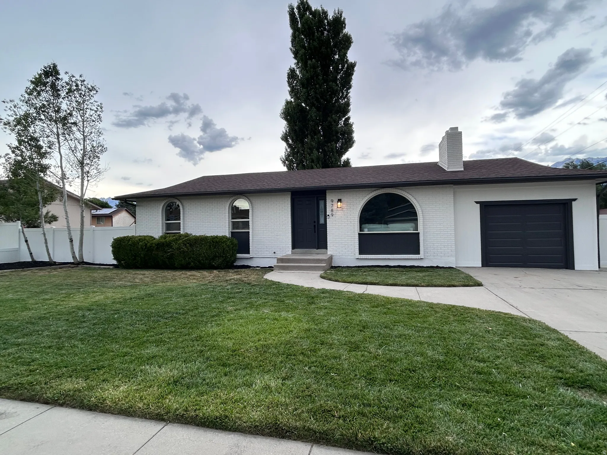 White brick exterior featuring a dark brown roof and matching garage door
