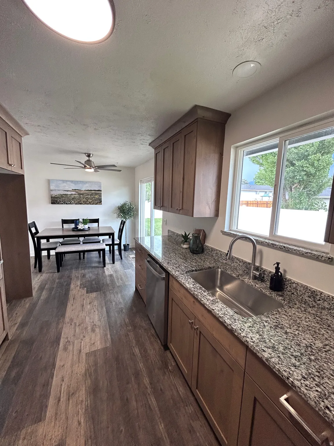 Kitchen featuring wood-finish flooring, granite countertops, stainless steel sink, and wood cabinetry
