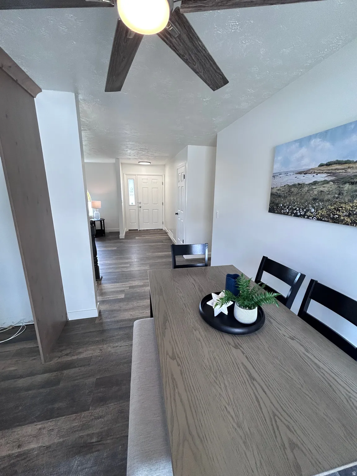 Open-concept dining area featuring wood-finish flooring, a contemporary ceiling fan, and a light-toned wood table