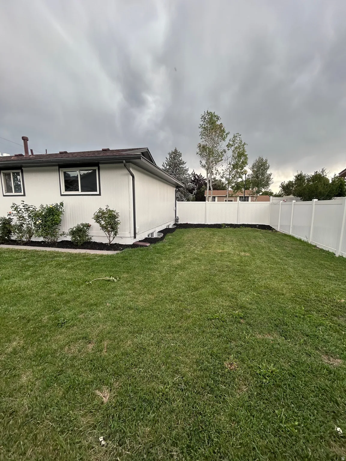 Expansive green lawn bordering a white vinyl privacy fence
