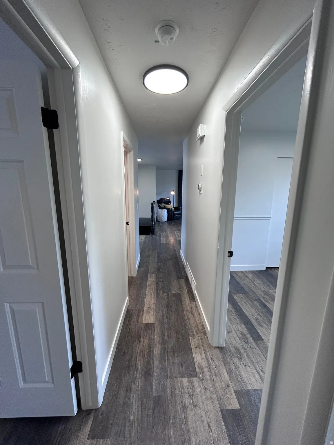 Hallway featuring wood-finish flooring, white trim, and a flush-mount ceiling light fixture