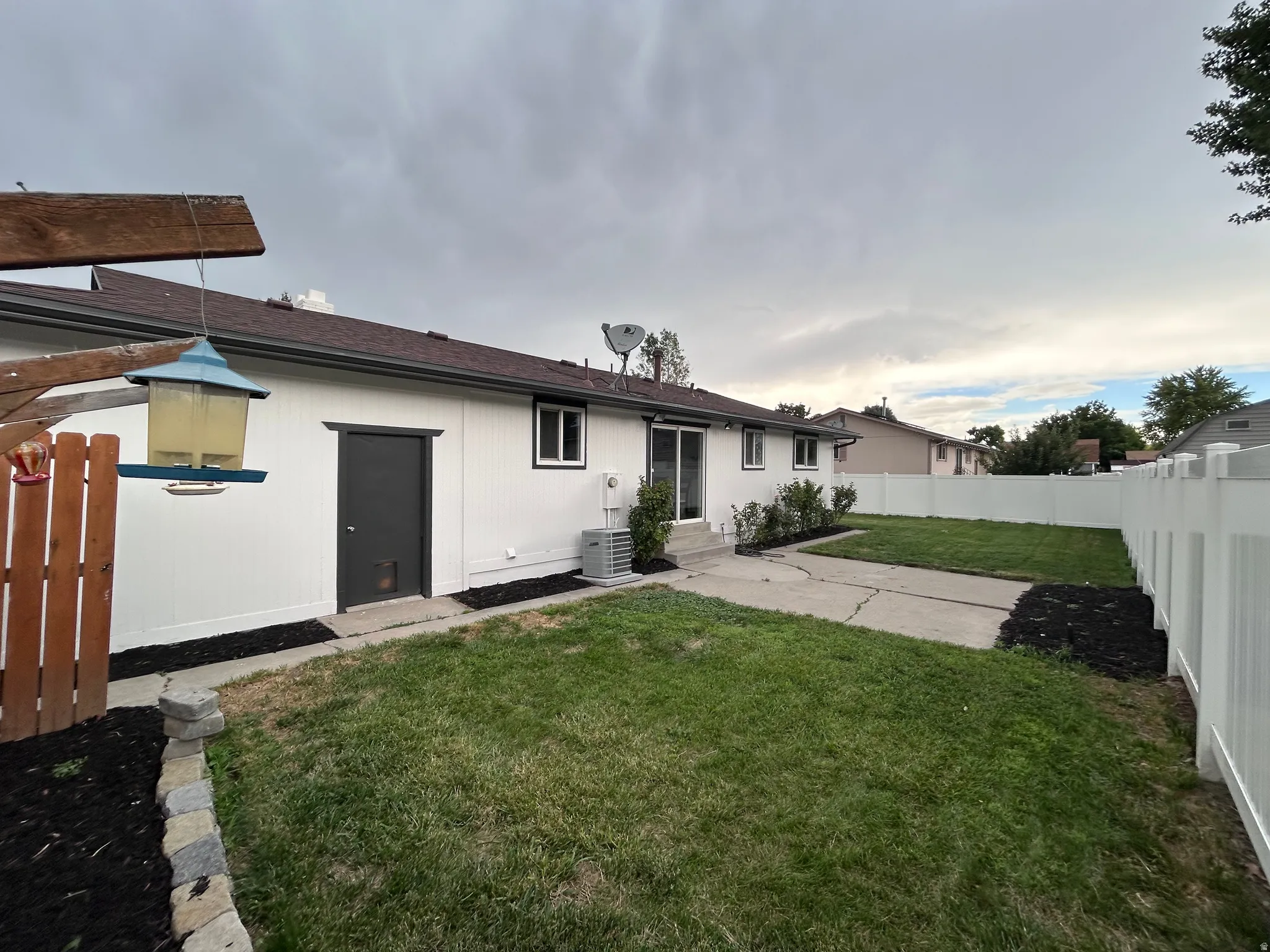 Expansive backyard featuring a white vinyl privacy fence, a concrete patio, and a well-maintained lawn