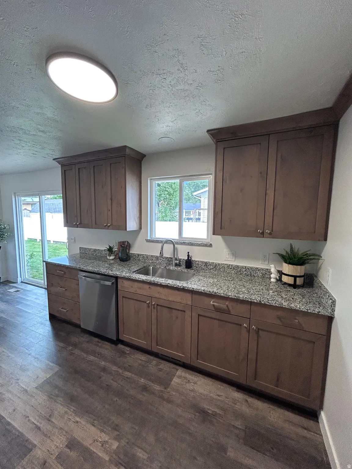 Kitchen featuring wood-finish cabinetry, granite-style countertops, and stainless steel appliances