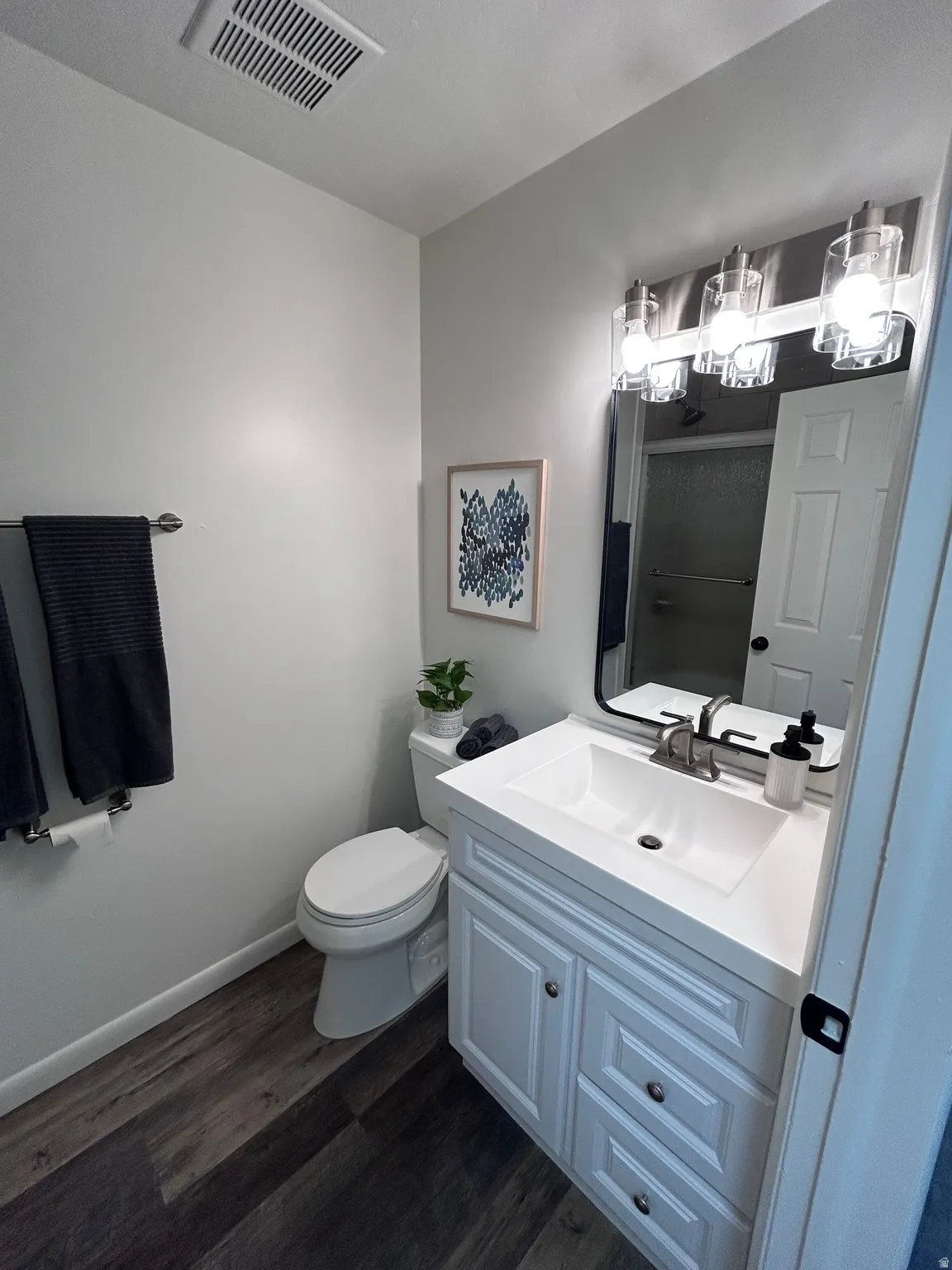 Contemporary bathroom featuring a white vanity with integrated sink, brushed nickel faucet, and multi-light vanity fixture
