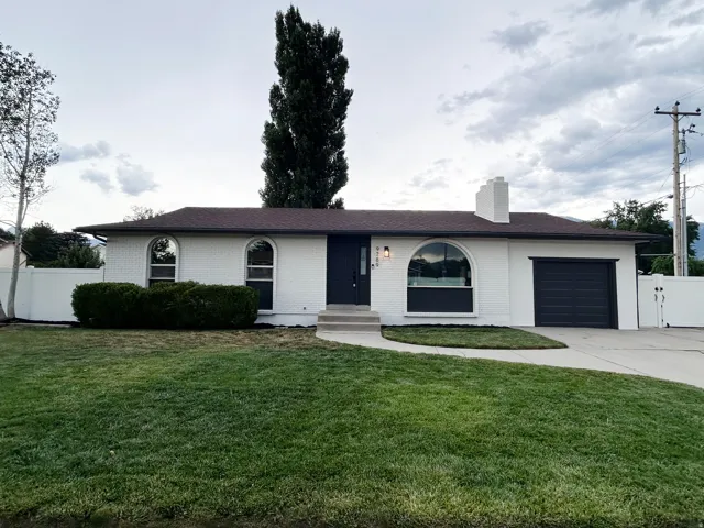 White brick exterior featuring a dark brown roof and arched windows