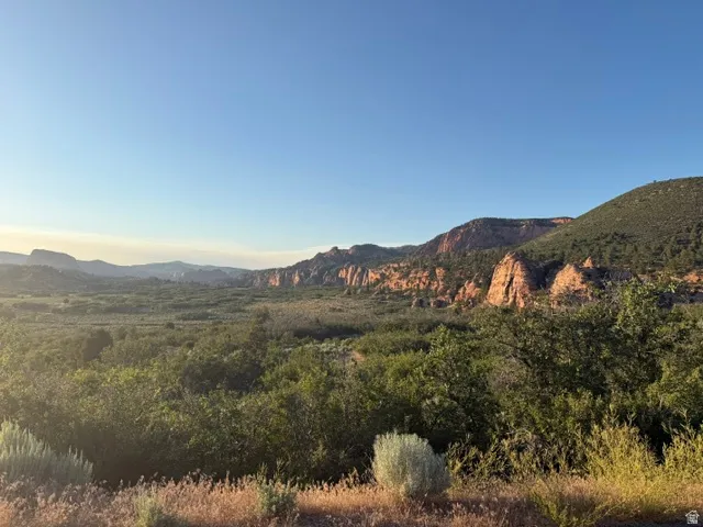 Expansive natural landscape featuring distant red rock formations and a clear blue sky
