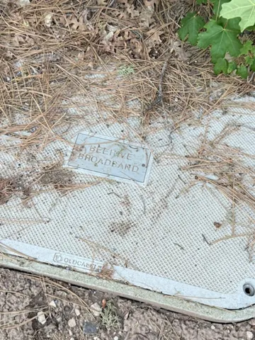 Utility access cover with textured grid pattern and Beehive Broadband marker
