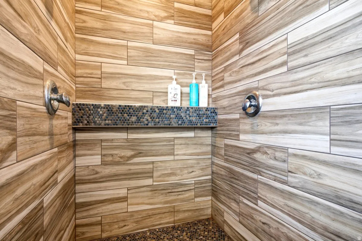 Shower with beautifully tiled walls, an integrated tiled niche with mosaic accents, and a pebble-finish floor