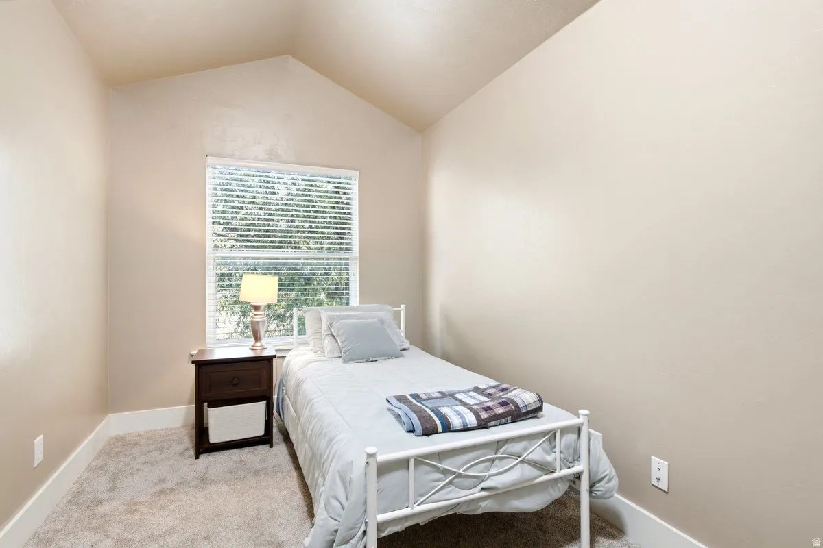Bedroom 4 with a vaulted ceiling and backyard views