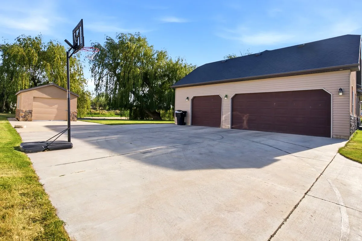 Expansive concrete driveway featuring 3 car attached garages, and a secondary detached garage structure.