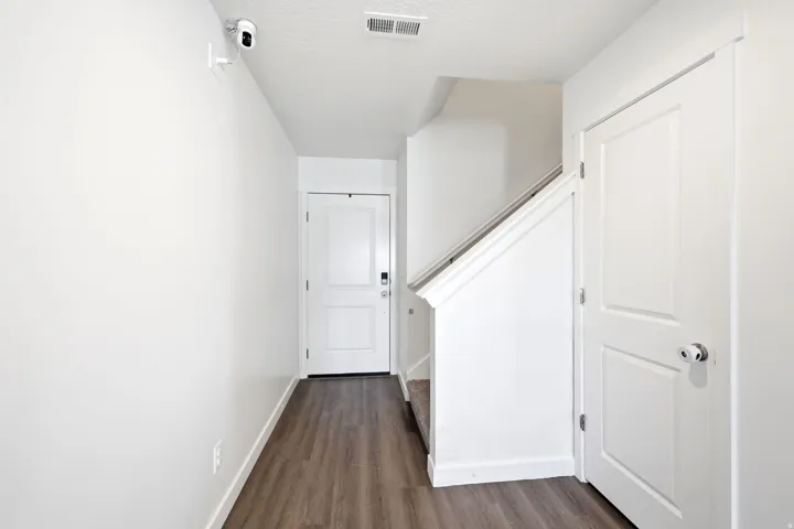 Entryway featuring wood-finish flooring, white paneled doors, and a staircase with a white railing