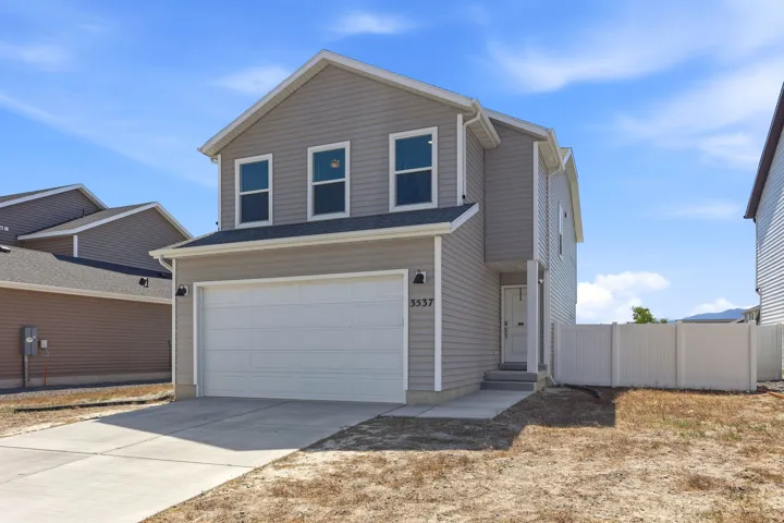 Two-story residence featuring light gray siding with white trim, an attached two-car garage, and a white privacy fence