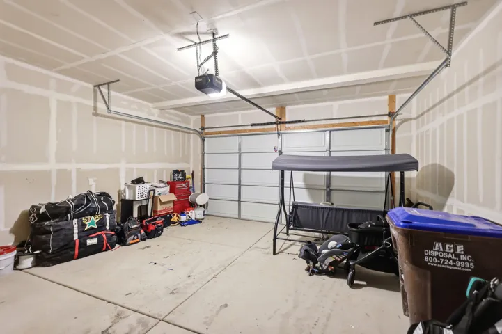 Attached garage featuring a sectional overhead door, concrete flooring, and an automatic garage door opener