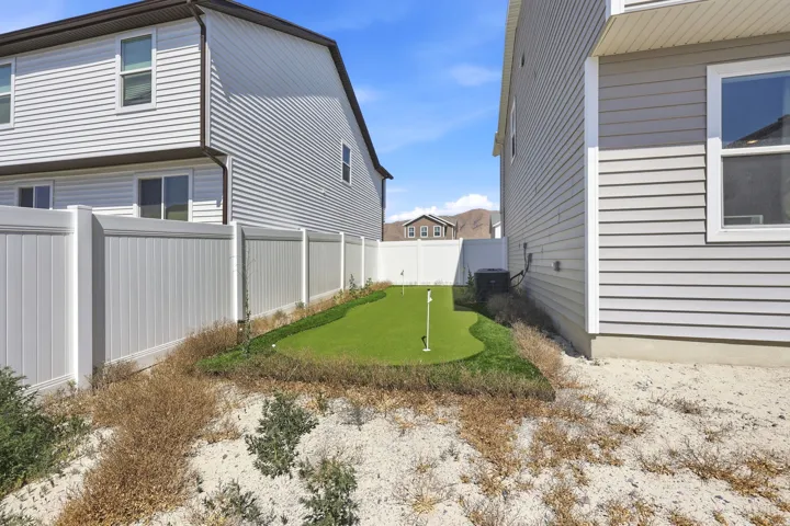 Outdoor putting green framed by a white vinyl fence