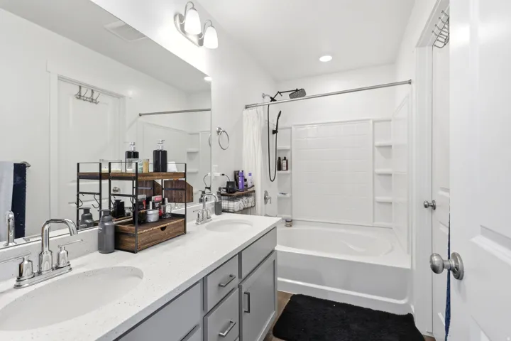 Bathroom featuring a double vanity with stone-finish countertops, undermount sinks, and grey shaker-style cabinetry