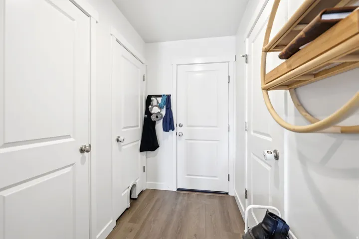 Entryway featuring wood-finish flooring, white paneled doors, and brushed nickel door hardware