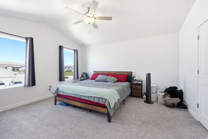 Spacious room featuring vaulted ceilings, light gray carpeting, and two large windows