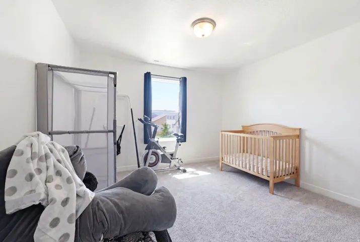 Light-filled room featuring neutral carpeting, white walls, and a large window with dark blue drapes