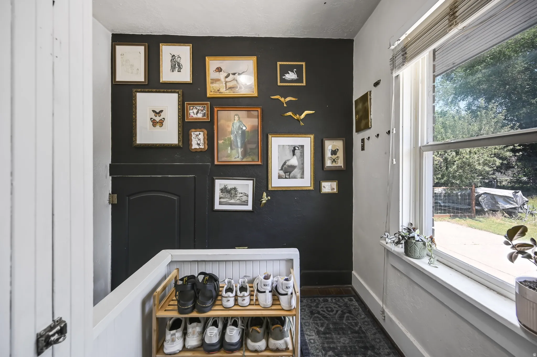 Hallway featuring a dark accent wall, a white painted railing with beadboard paneling, and a single window with blinds