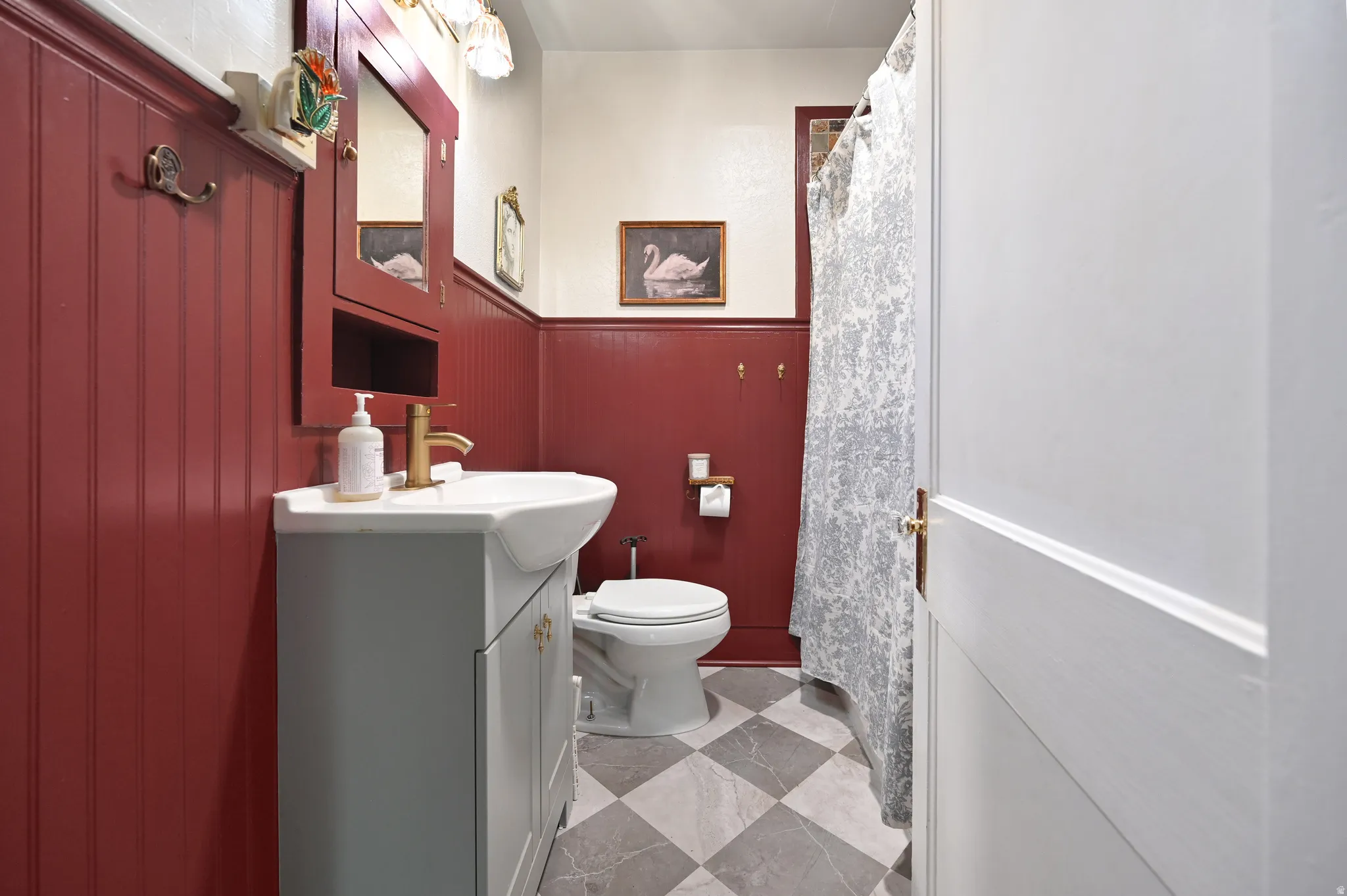 Bathroom featuring red wainscoting, a white vanity with an integrated sink, and a gold-finish faucet