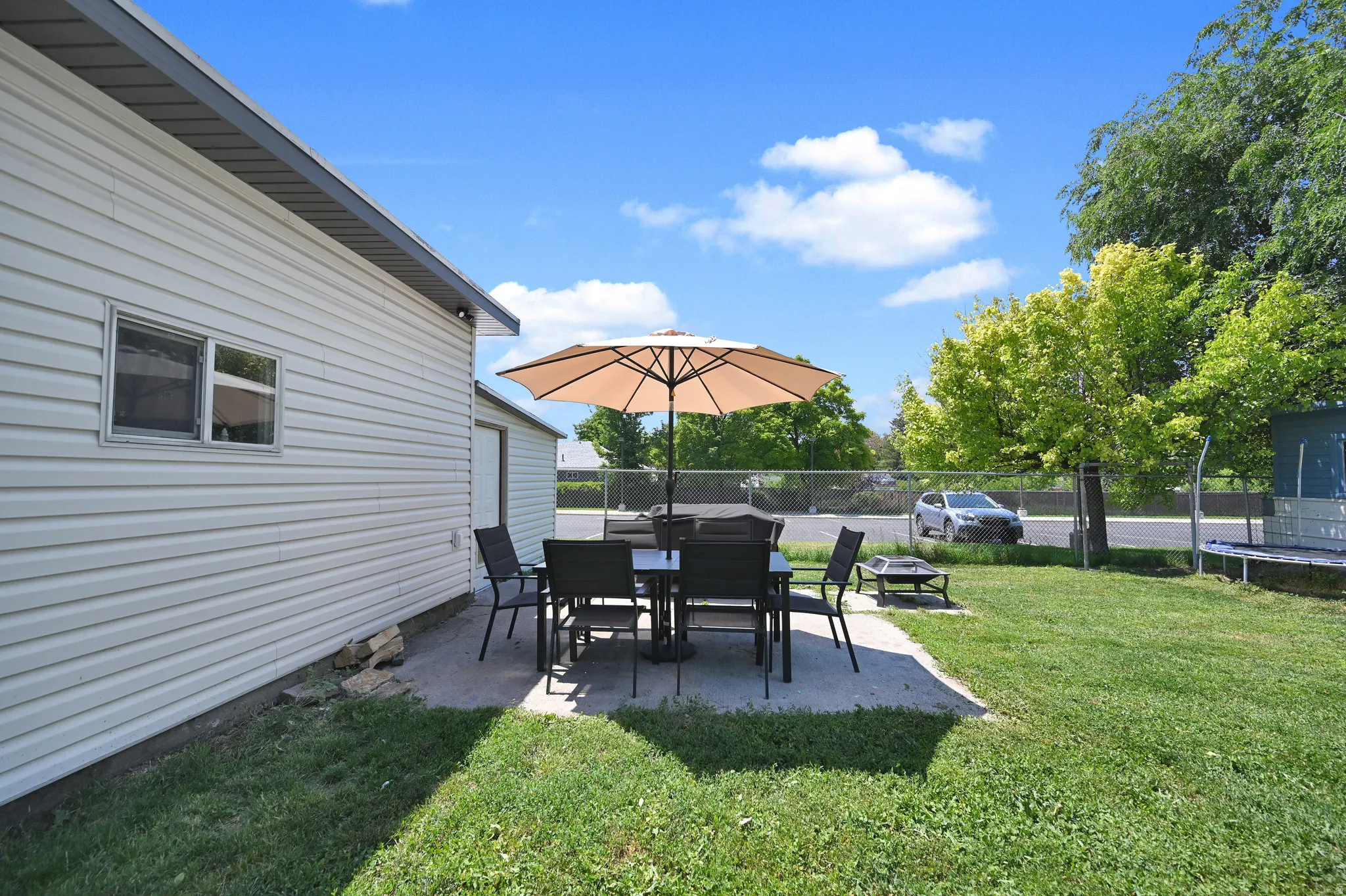 Concrete patio area featuring a table and chairs, bordered by a manicured lawn