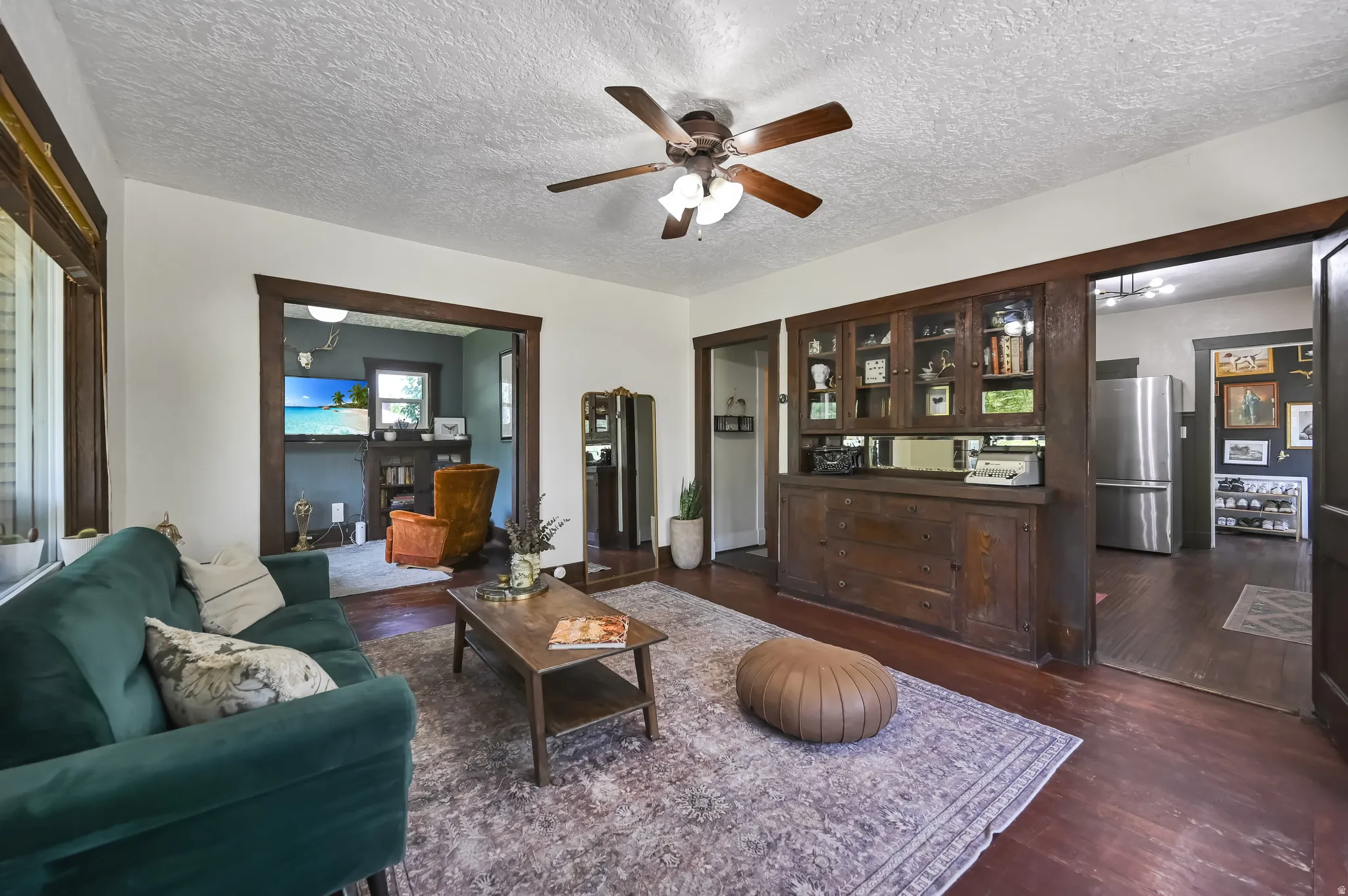 Living area featuring wood-finish flooring, a ceiling fan with integrated lighting, and white walls
