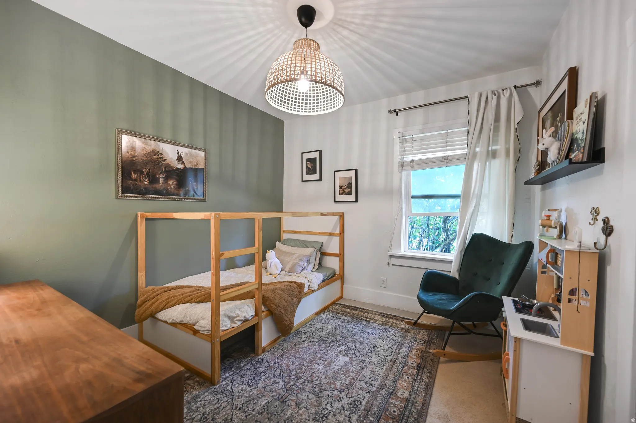 Bedroom featuring a soft green accent wall, wood-finish flooring, and a window with blinds and drapes