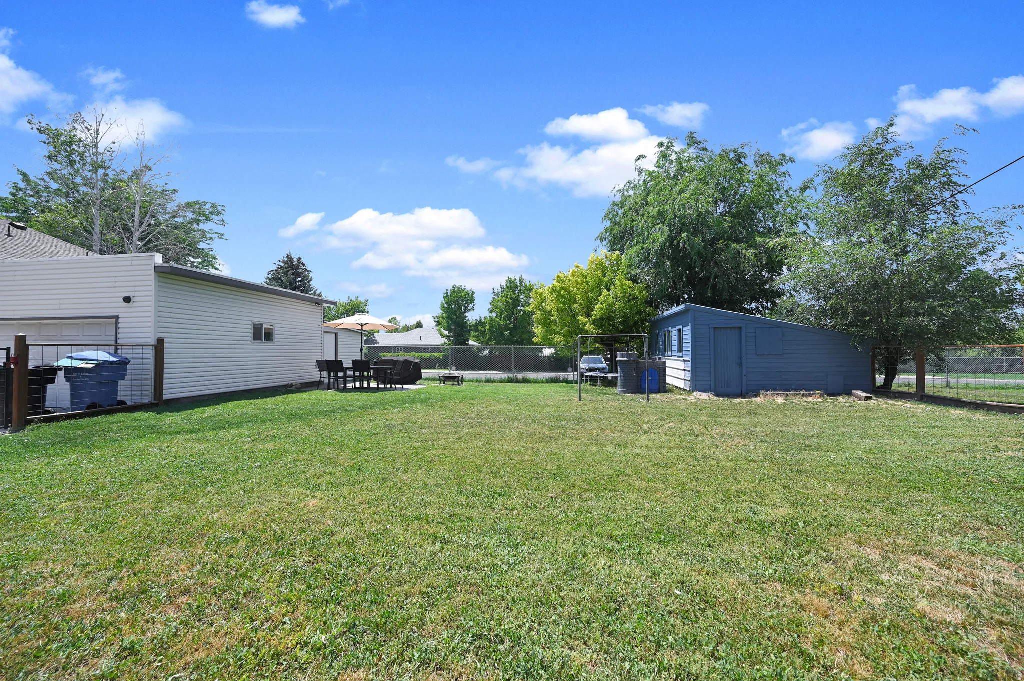 Grassy yard area featuring mature trees and a detached shed structure