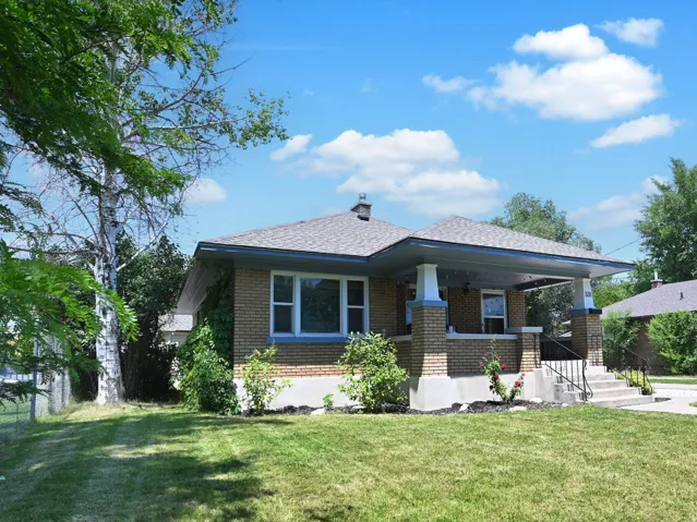 Brick exterior featuring a covered porch with column supports and a shingled roof