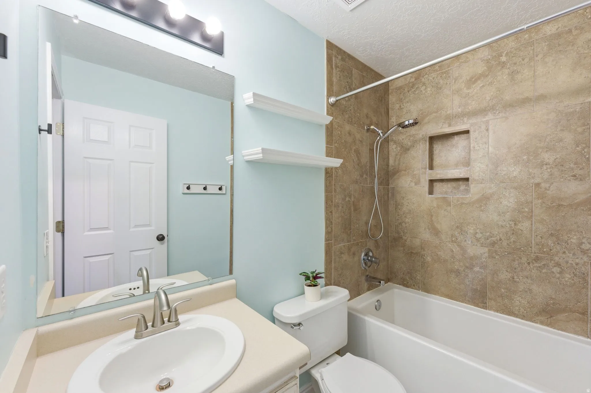 Bathroom featuring a white vanity with an oval undermount sink, brushed nickel faucet, and light-colored countertop