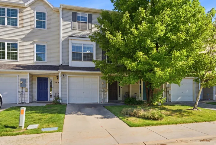 Two-story townhouse exterior with light siding, a single-car garage, and a front porch