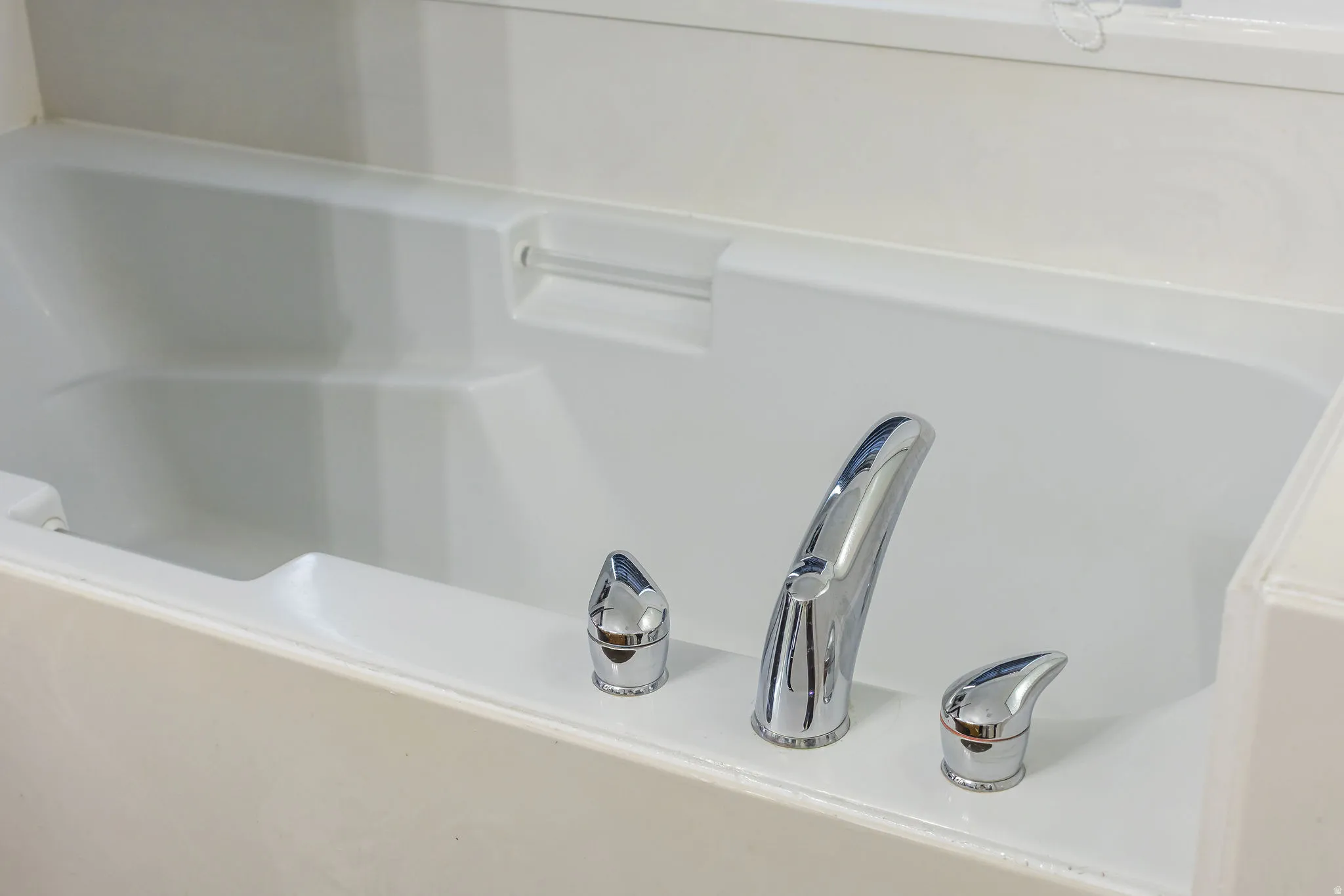 Built-in white soaking tub featuring chrome fixtures and a surrounding white tile surface