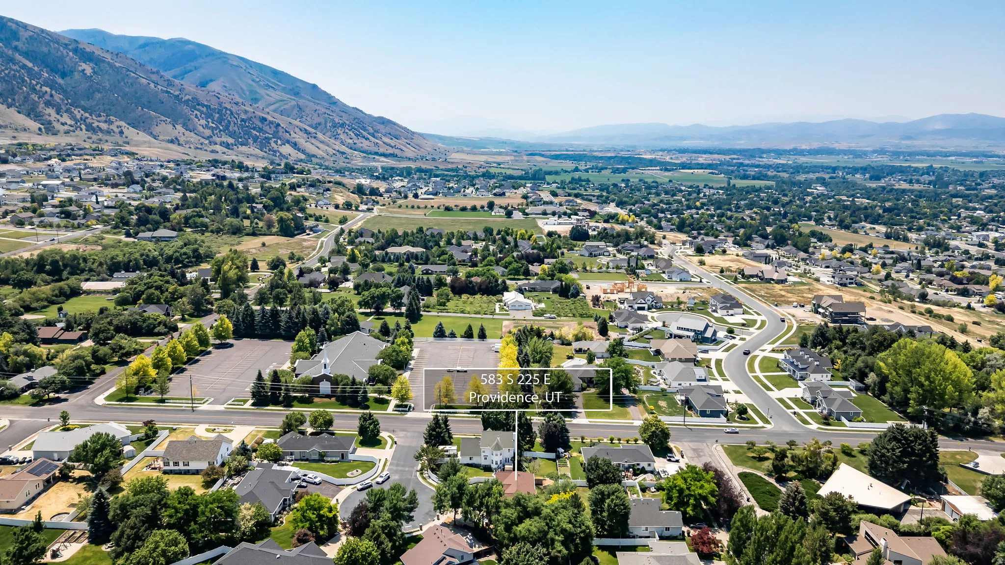 Expansive aerial showcasing a residential neighborhood with surrounding mountains and green spaces