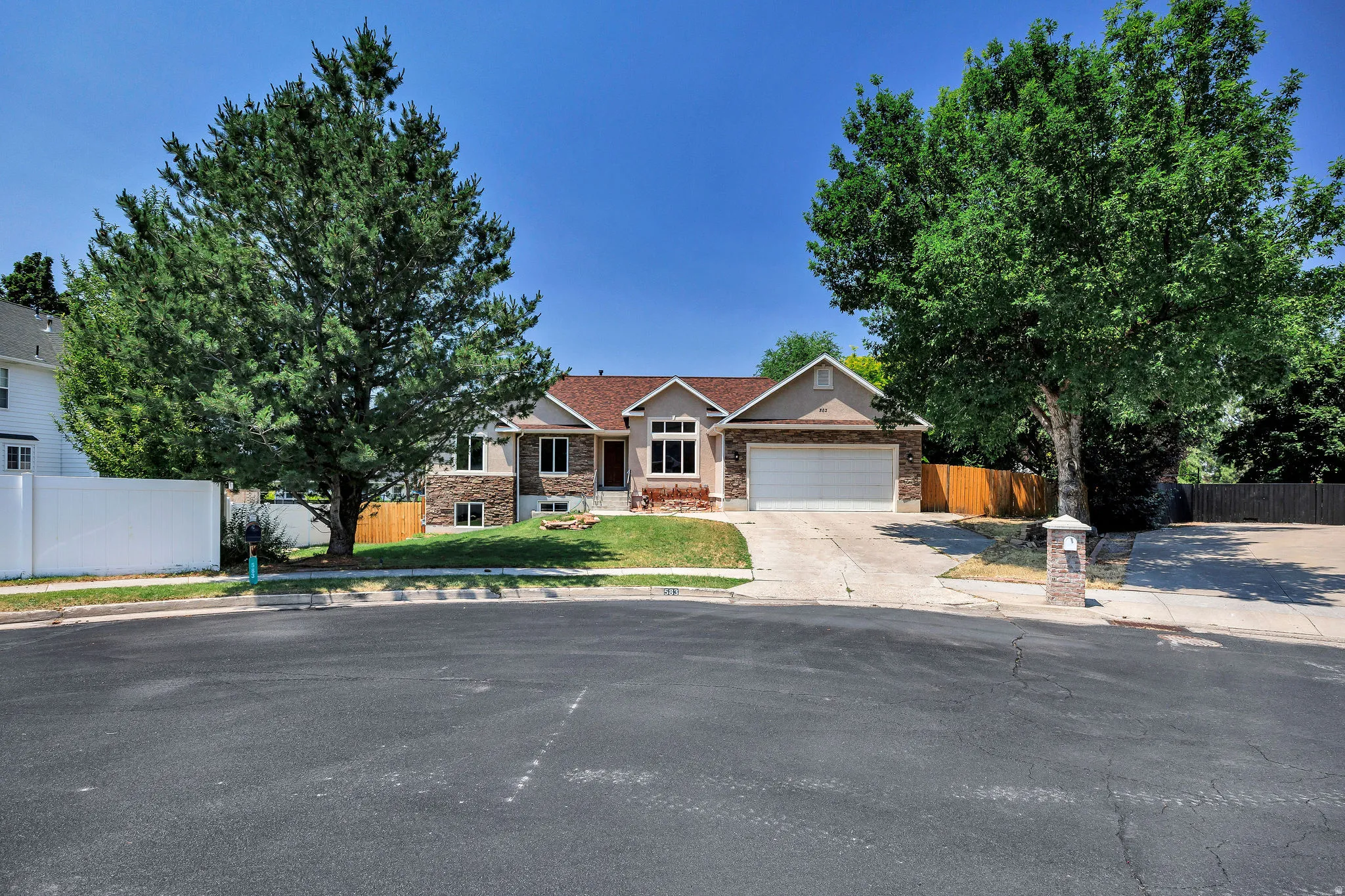 Single-story residence featuring a two-car garage, stone and stucco exterior, and a gabled roof
