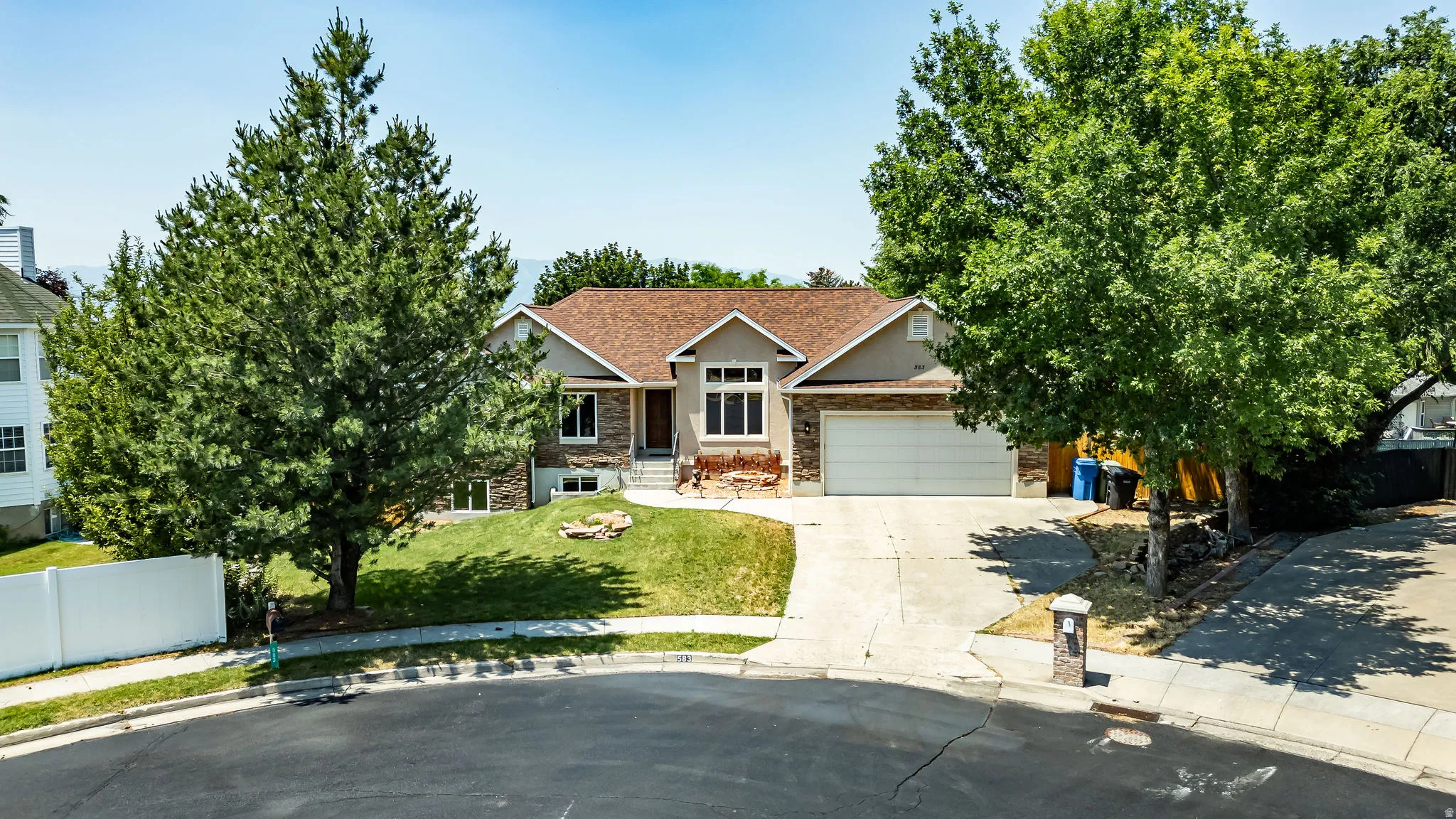 Contemporary residence featuring a two-car garage, stone and stucco facade, and a prominent front entrance