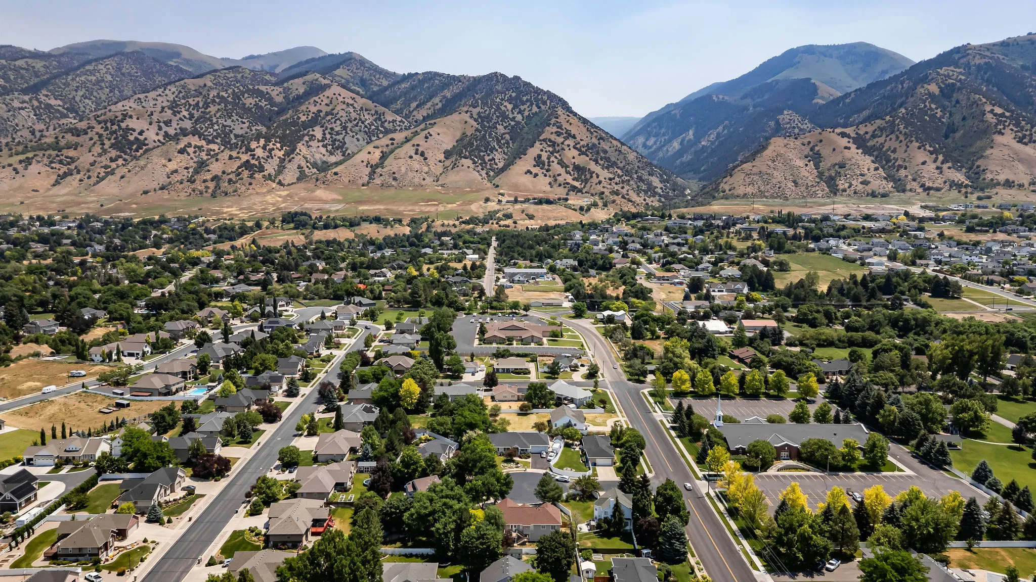 Residential community bordered by mountains, featuring established homes, mature trees, and a developed road network
