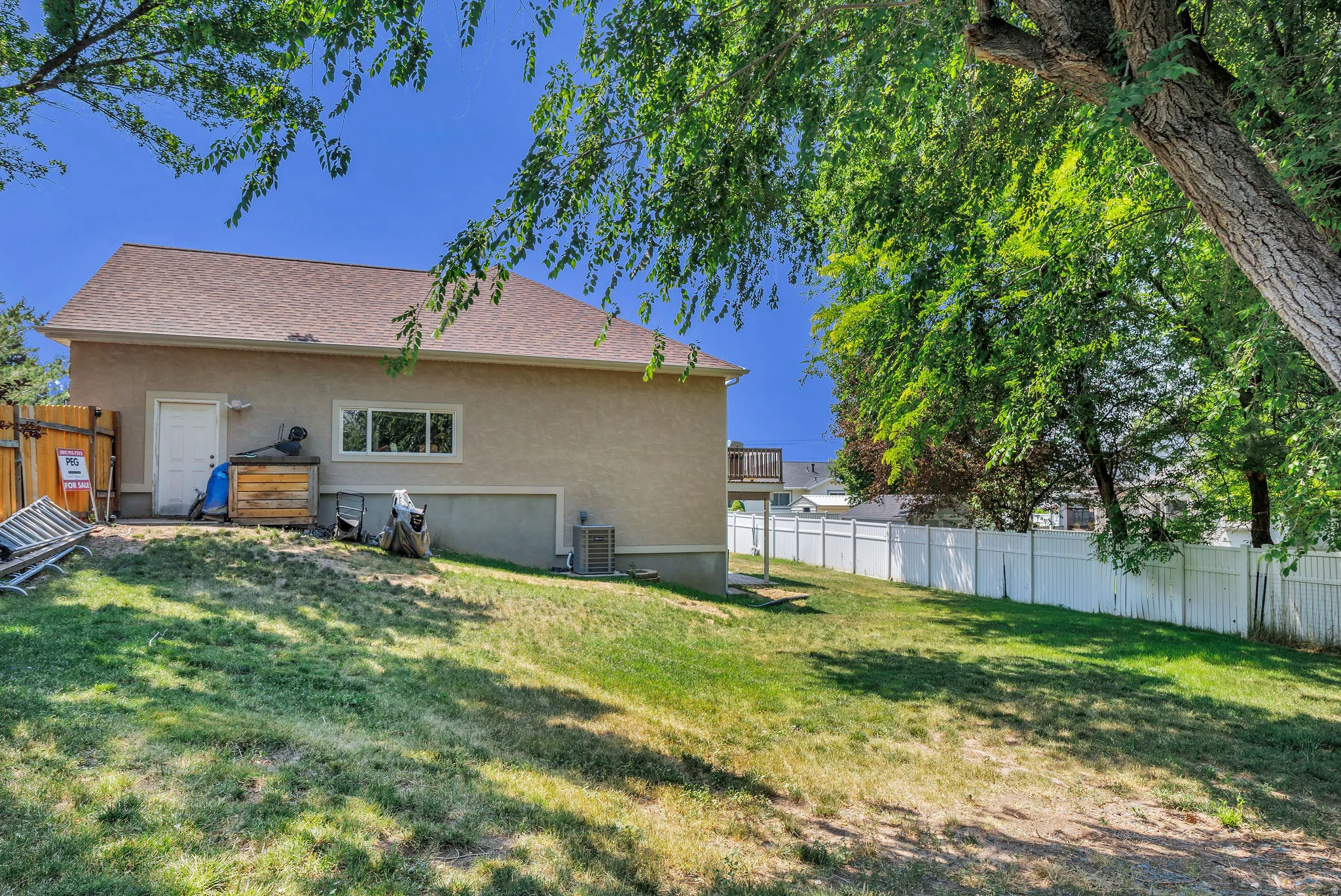 Spacious rear yard with a gentle slope and mature trees providing natural shade