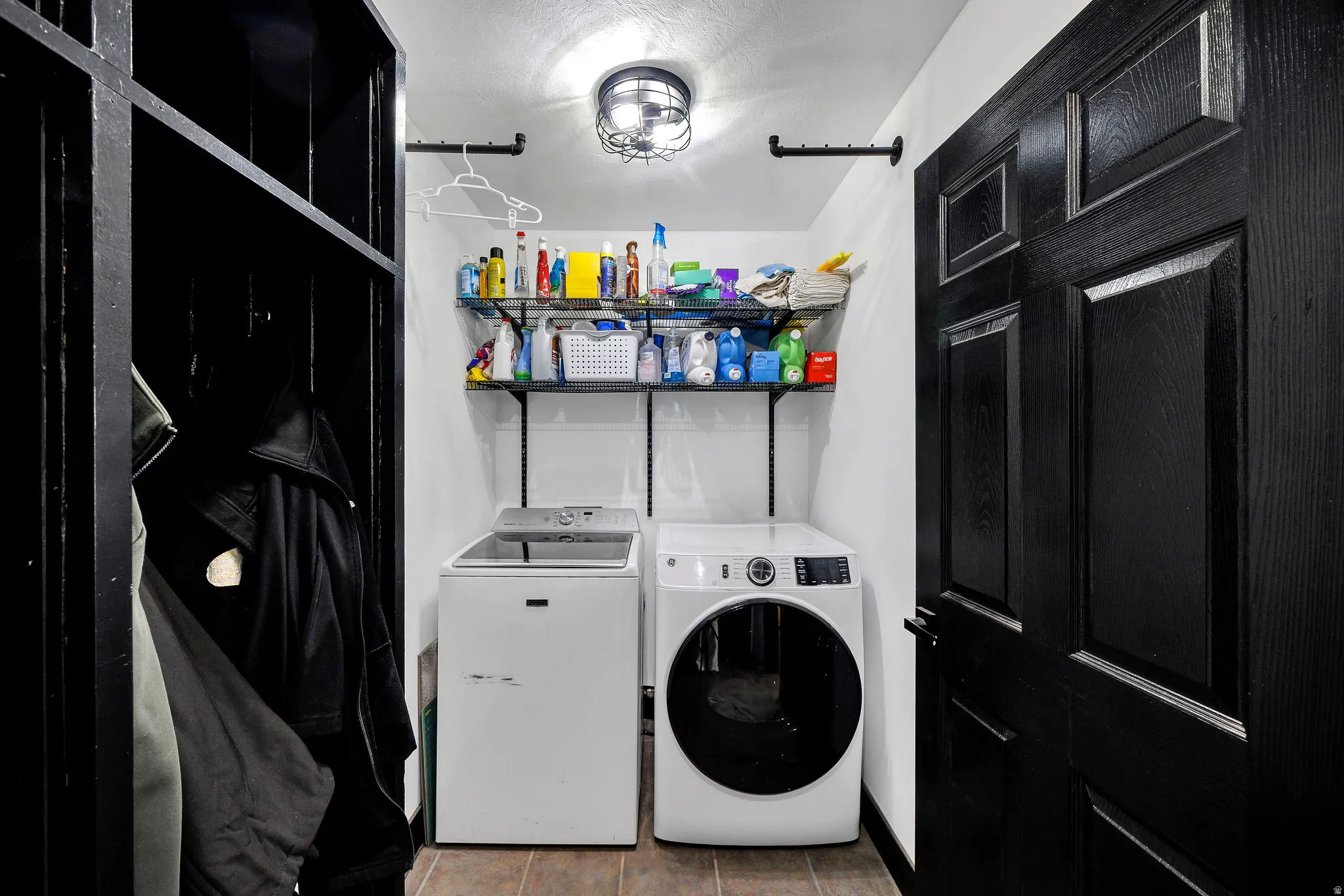 Dedicated laundry space featuring tile flooring and overhead shelving